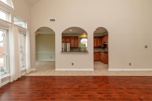 unfurnished living room featuring visible vents, high vaulted ceiling, recessed lighting, light wood-style floors, and baseboards