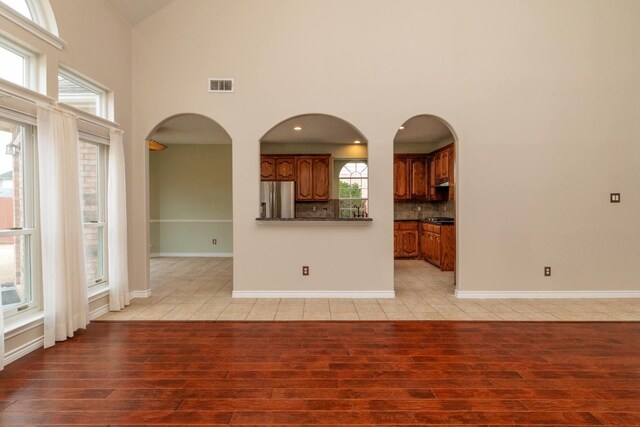 kitchen with a kitchen island, under cabinet range hood, appliances with stainless steel finishes, brown cabinetry, and a sink