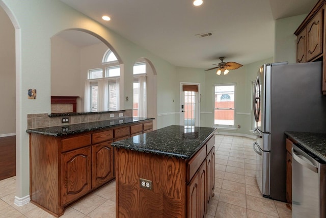 kitchen featuring visible vents, dark stone countertops, a center island, appliances with stainless steel finishes, and light tile patterned floors