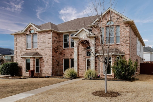 view of front of house featuring brick siding and roof with shingles