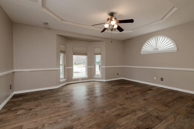 spare room featuring a tray ceiling, a healthy amount of sunlight, and wood finished floors