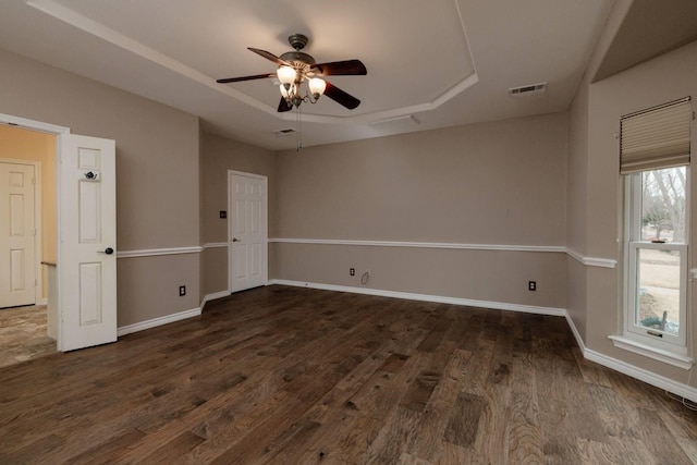 unfurnished room with visible vents, a raised ceiling, baseboards, and wood finished floors