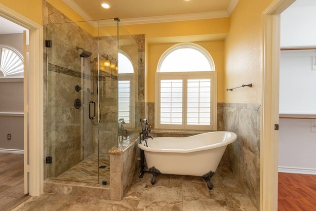 full bath with crown molding, wainscoting, a stall shower, a freestanding tub, and tile walls