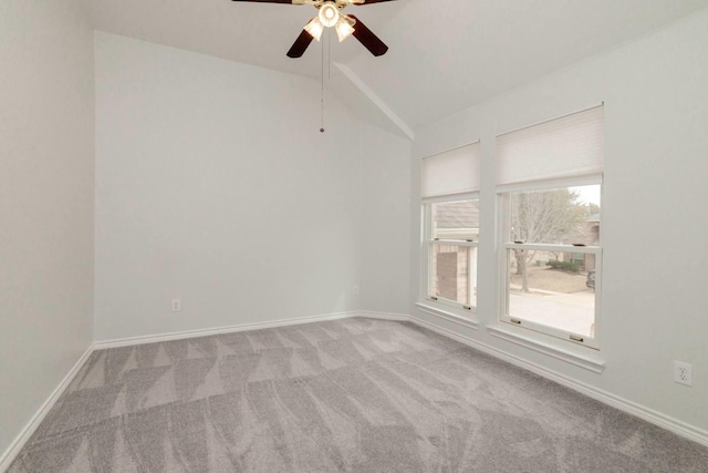 carpeted empty room featuring ceiling fan, baseboards, and vaulted ceiling