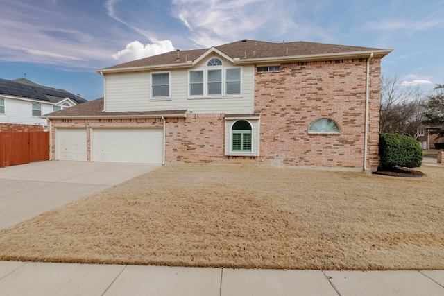 view of front facade with concrete driveway, a garage, fence, and brick siding