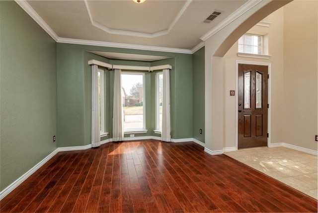 entrance foyer featuring visible vents, ornamental molding, wood finished floors, arched walkways, and baseboards