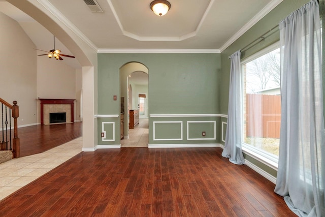 unfurnished room featuring visible vents, arched walkways, wood finished floors, and stairs