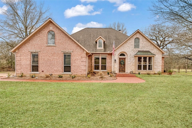 view of front of home with brick siding, a shingled roof, and a front lawn