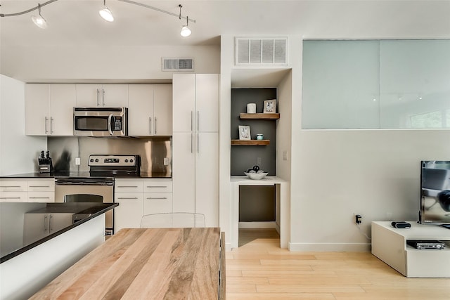 kitchen with visible vents, white cabinets, appliances with stainless steel finishes, dark countertops, and light wood-type flooring