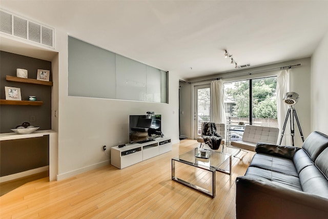 living area with track lighting, light wood-style floors, visible vents, and baseboards