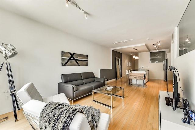 living room featuring light wood finished floors, track lighting, and a chandelier