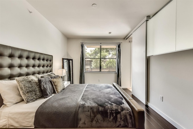 bedroom with dark wood-style floors and baseboards