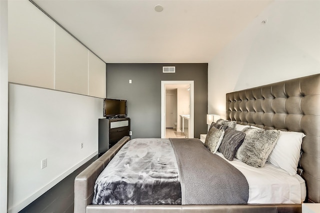 bedroom with baseboards, visible vents, and ensuite bathroom