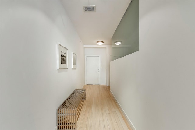 hallway featuring visible vents, light wood-type flooring, and baseboards