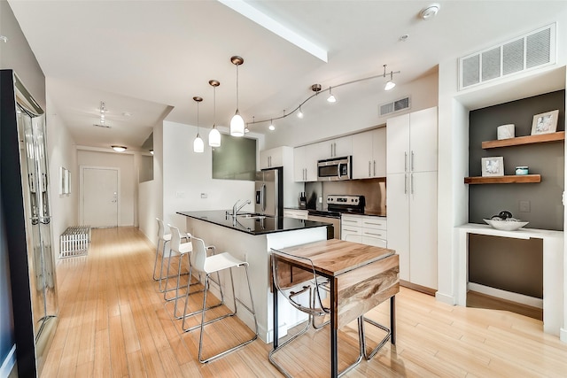 kitchen with dark countertops, visible vents, a breakfast bar area, and stainless steel appliances