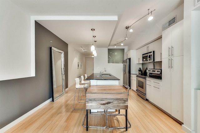 kitchen featuring visible vents, a sink, dark countertops, stainless steel appliances, and light wood finished floors