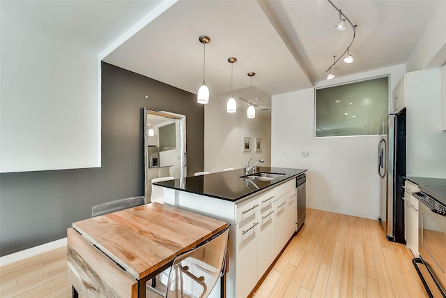 kitchen featuring white cabinets, appliances with stainless steel finishes, light wood-type flooring, and a sink