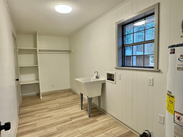 clothes washing area featuring water heater, laundry area, hookup for a washing machine, and light wood finished floors