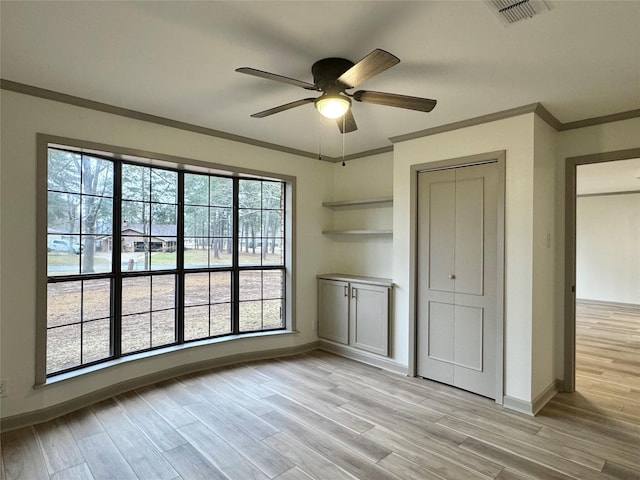 unfurnished bedroom featuring baseboards, light wood-style floors, visible vents, and ornamental molding