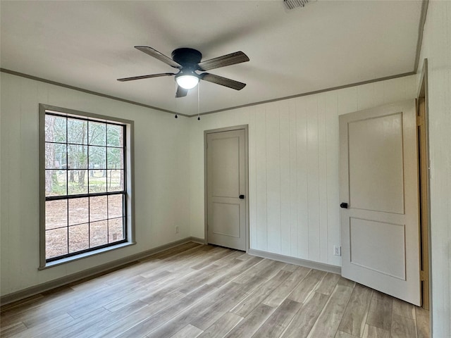 unfurnished bedroom with light wood-style floors, baseboards, and ornamental molding