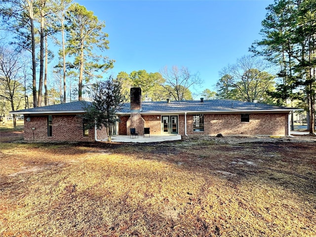 rear view of property featuring a patio area, brick siding, and a chimney