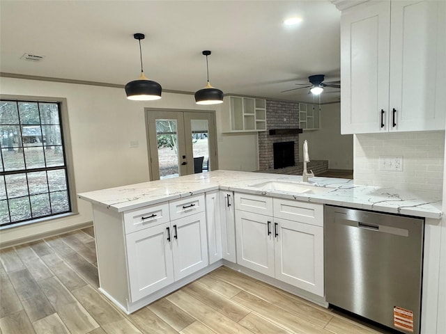 kitchen with a sink, tasteful backsplash, stainless steel dishwasher, open floor plan, and a peninsula