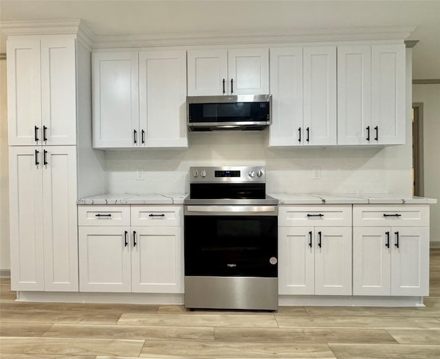 kitchen with white cabinetry, light wood-style flooring, light stone counters, and appliances with stainless steel finishes