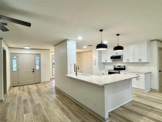 kitchen featuring light wood finished floors, light stone counters, appliances with stainless steel finishes, white cabinetry, and a sink