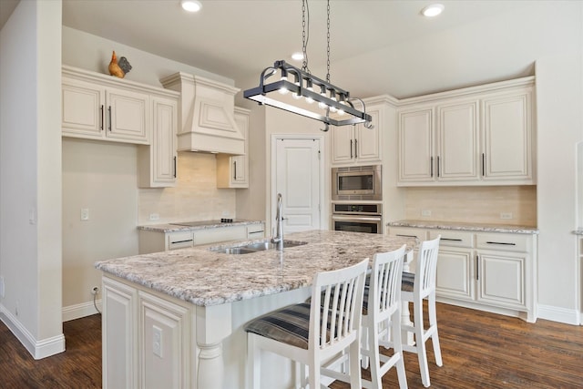 kitchen with premium range hood, dark wood-style flooring, a sink, stainless steel appliances, and backsplash