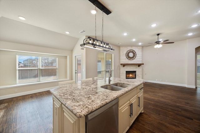 kitchen with open floor plan, dishwasher, a fireplace, plenty of natural light, and a sink