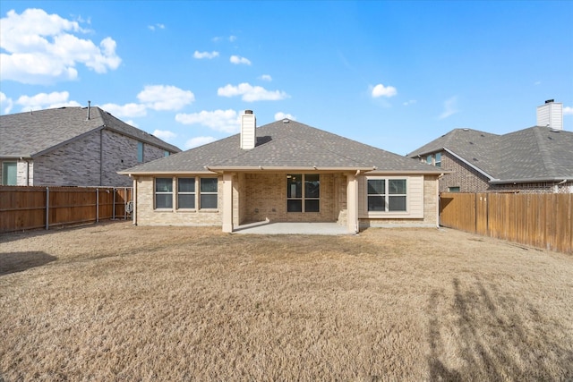 rear view of property featuring brick siding, a patio area, a chimney, and a fenced backyard