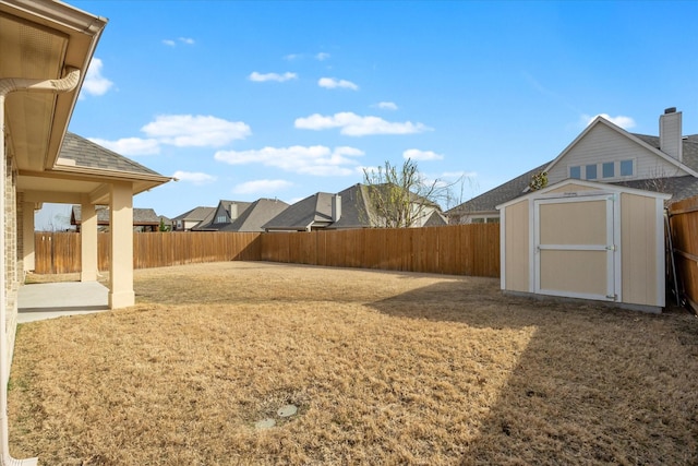 view of yard with an outdoor structure, a storage unit, a fenced backyard, and a patio