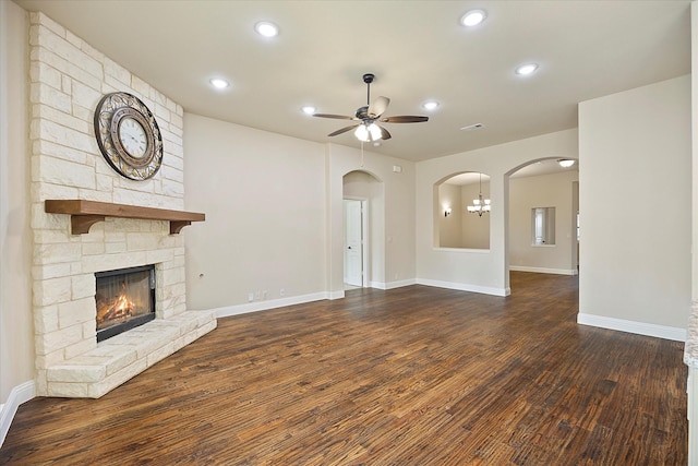 unfurnished living room with arched walkways, recessed lighting, a fireplace, and wood finished floors