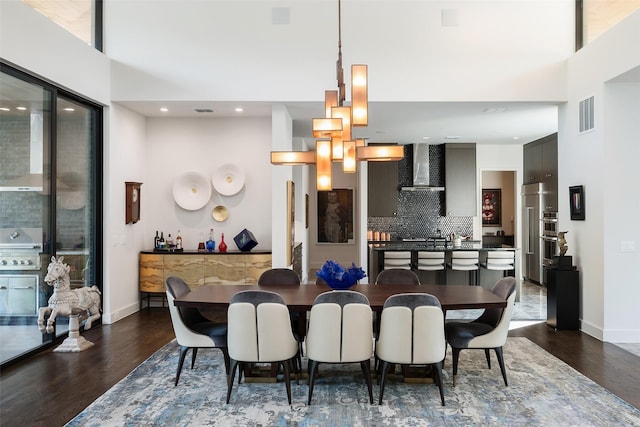 dining space featuring visible vents, dark wood-style flooring, a towering ceiling, and baseboards