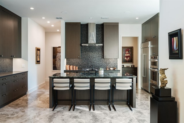 kitchen with visible vents, a kitchen bar, and wall chimney range hood