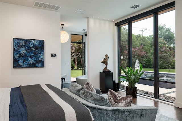 bedroom with a wall of windows, visible vents, and wood finished floors