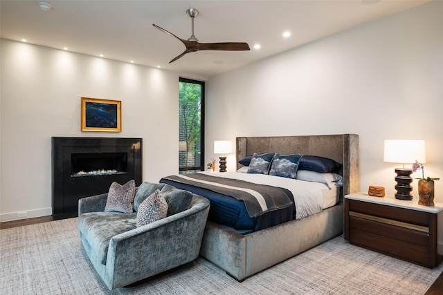 bedroom featuring recessed lighting, a warm lit fireplace, and ceiling fan