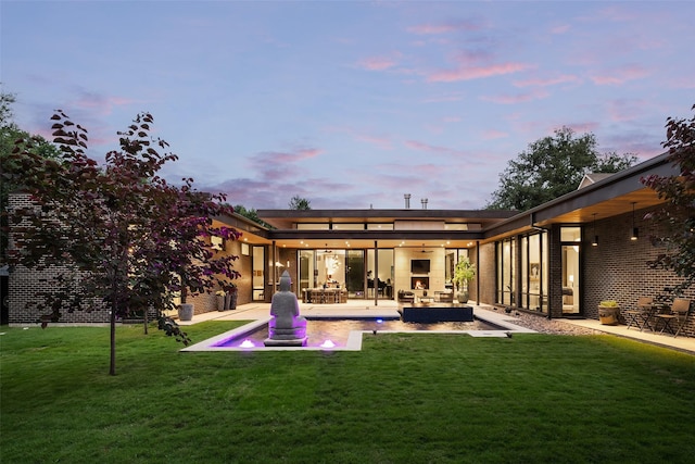 back of house at dusk featuring an outdoor hangout area, a lawn, a patio, and ceiling fan