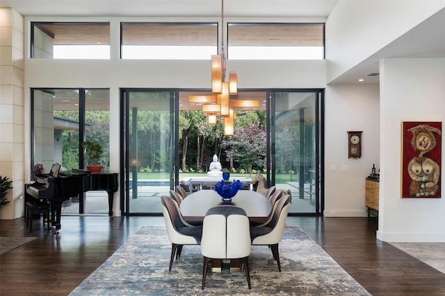 dining space with a notable chandelier, a high ceiling, baseboards, and wood finished floors