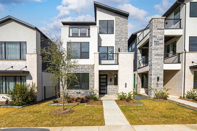 contemporary home featuring a front yard, stone siding, and stucco siding