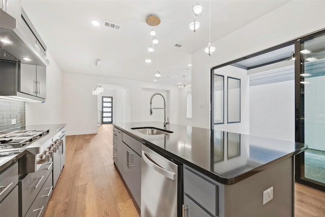 kitchen with visible vents, gray cabinets, stainless steel appliances, a sink, and exhaust hood