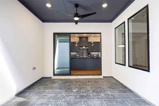 doorway to property with ceiling fan and a sink