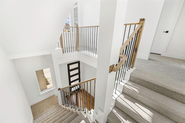 staircase featuring a high ceiling, baseboards, and carpet floors