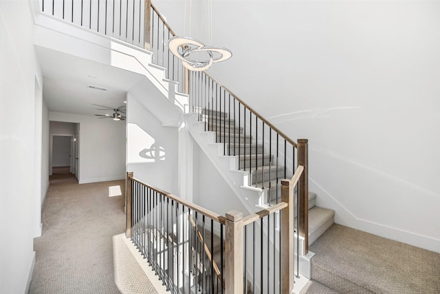 stairway featuring visible vents, carpet floors, a high ceiling, and baseboards