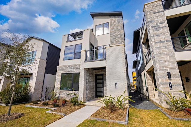 modern home with stucco siding, stone siding, brick siding, and a front lawn