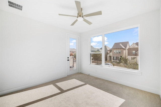 unfurnished room featuring a ceiling fan, light colored carpet, visible vents, and baseboards