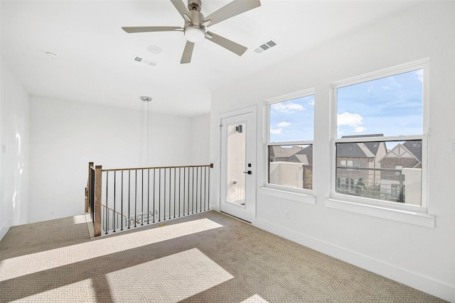 carpeted spare room featuring visible vents, a ceiling fan, and baseboards