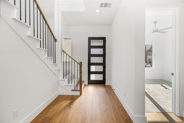 foyer featuring visible vents, stairs, baseboards, and wood finished floors