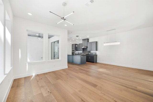 unfurnished living room featuring baseboards, visible vents, recessed lighting, light wood-style floors, and a chandelier