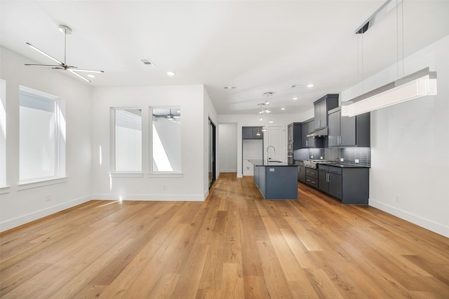 kitchen featuring ceiling fan, a sink, dark countertops, open floor plan, and backsplash